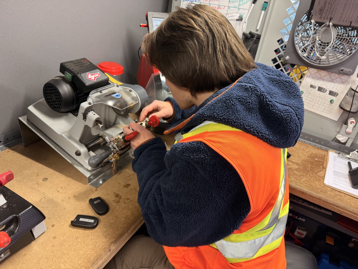 A Visma Promotions technician precisely cutting an automotive key using professional key cutting equipment